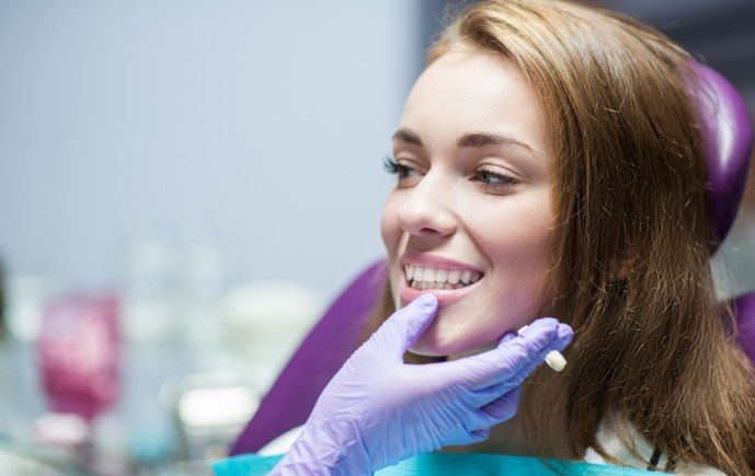 Dentist examining woman's smile after dental crown treatment
