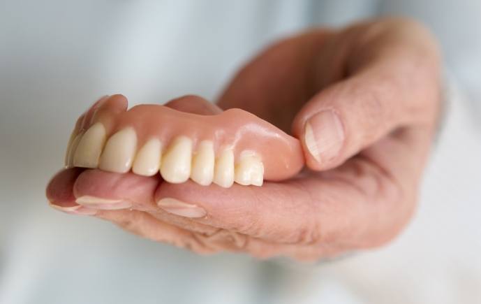 Hand holding a full denture