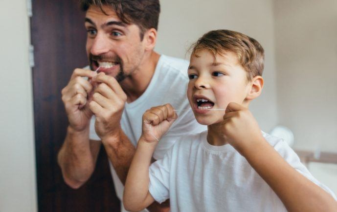 Father and child flossing teeth to prevent dental emergencies