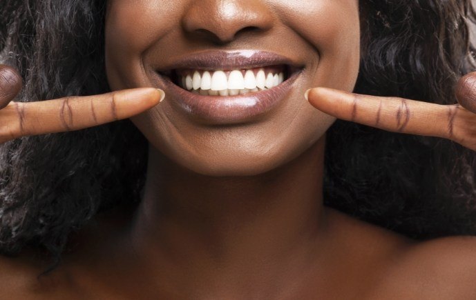 Dental patient pointing to smile after periodontal therapy for gum disease