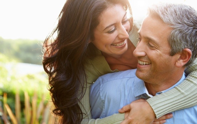 Smiling man and woman enjoying the benefits of dental implants