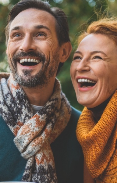 Man and woman with full smiles after replacing missing teeth