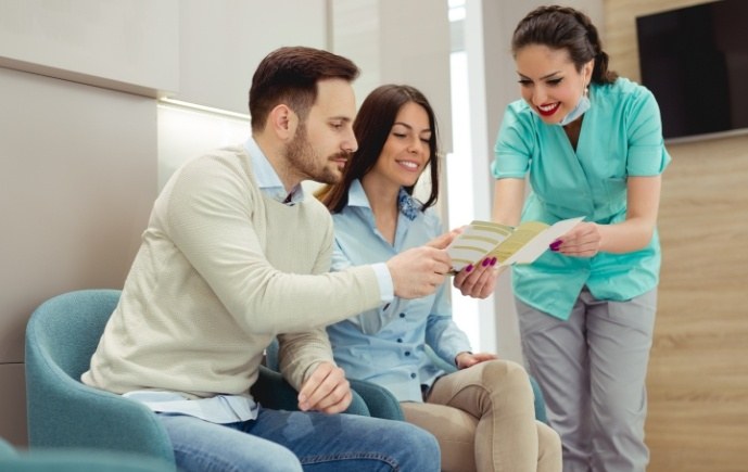 Dental team member and dentistry patients reviewing dental insurance information