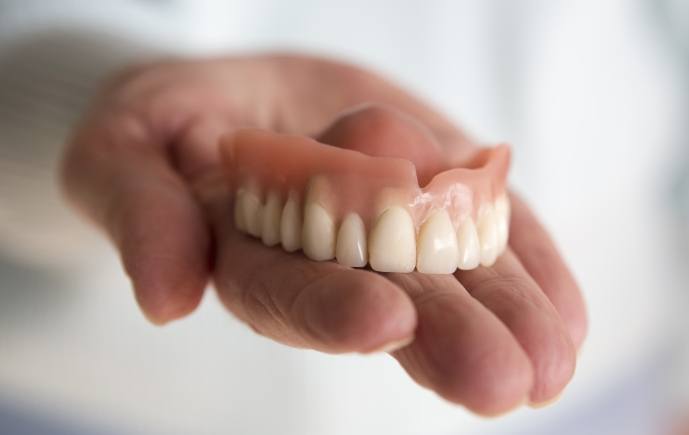 Hand holding full denture