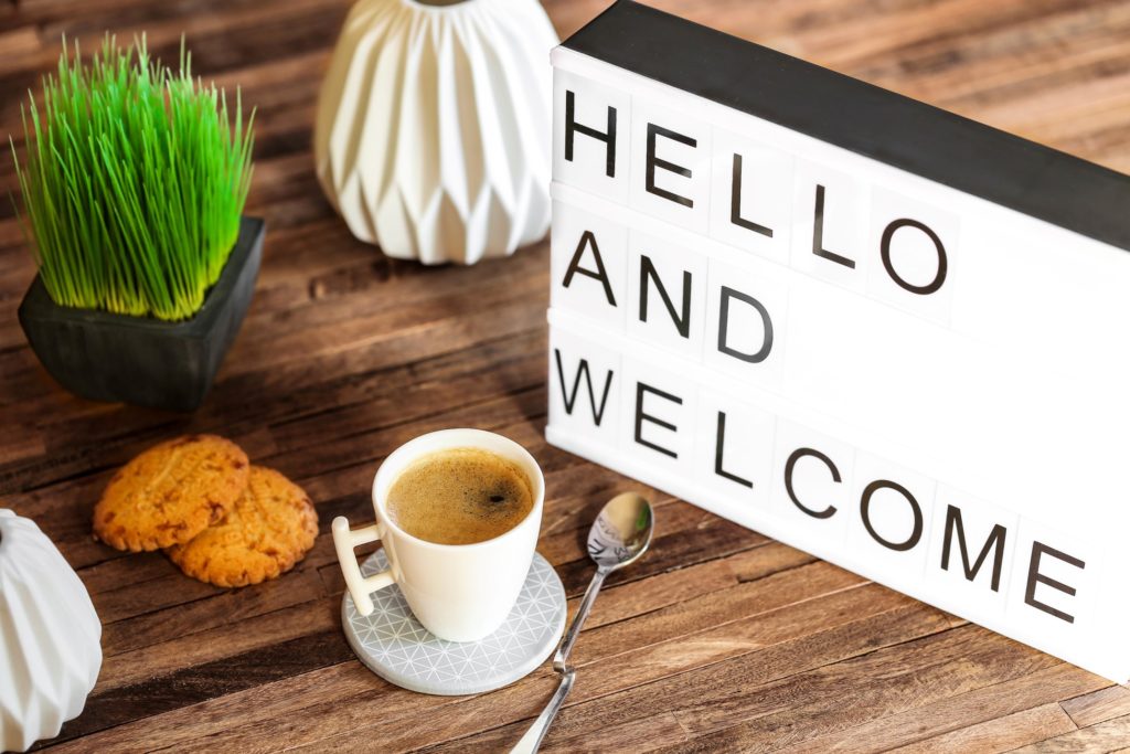 Hello and welcome sign on desk with coffee